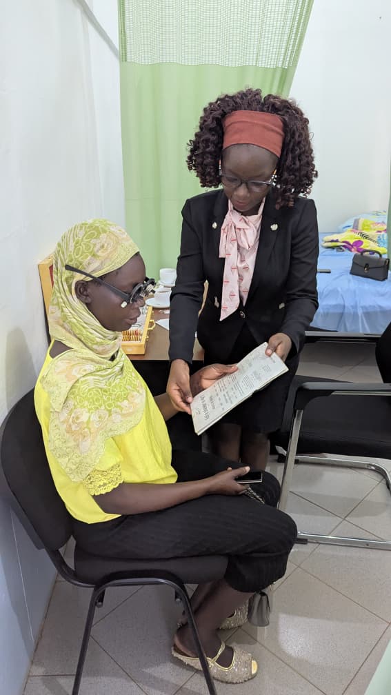 A nurse hands a prescription slip to a woman wearing a hijab during an eye clinic